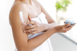 Femme appliquant une crème émolliente apaisante sur son bras pour soulager des démangeaisons cutanées persistantes.